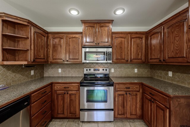 2056 Balsam Gap, Tyler, TX 75703 - kitchen with dark countertops, brown cabinetry, appliances with stainless steel finishes, and tasteful backsplash