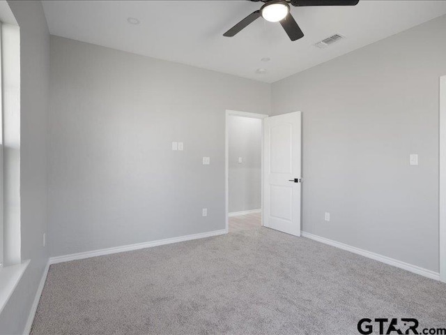 spare room featuring carpet, visible vents, ceiling fan, and baseboards