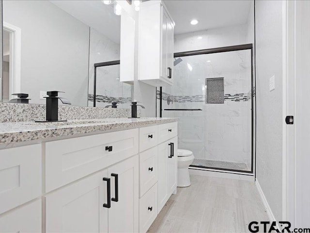 full bathroom featuring double vanity, a marble finish shower, and toilet