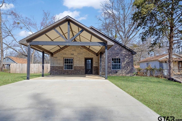 view of front facade featuring concrete driveway, a front lawn, fence, and brick siding