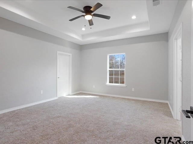 empty room featuring recessed lighting, baseboards, a raised ceiling, and light colored carpet