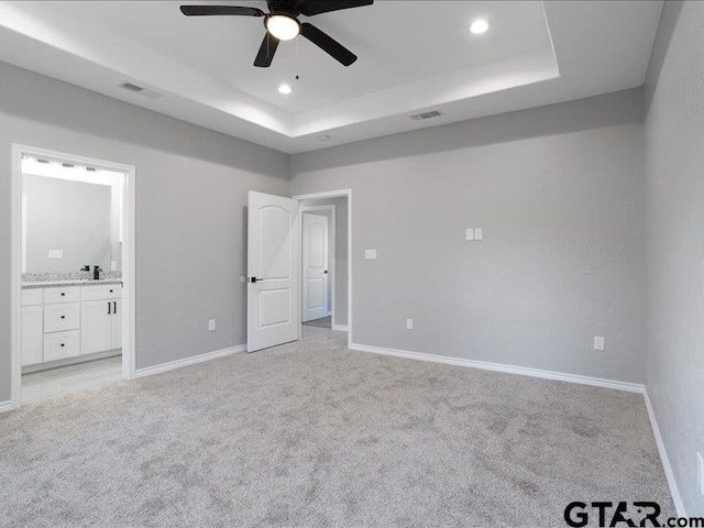 unfurnished bedroom with recessed lighting, light carpet, visible vents, baseboards, and a raised ceiling