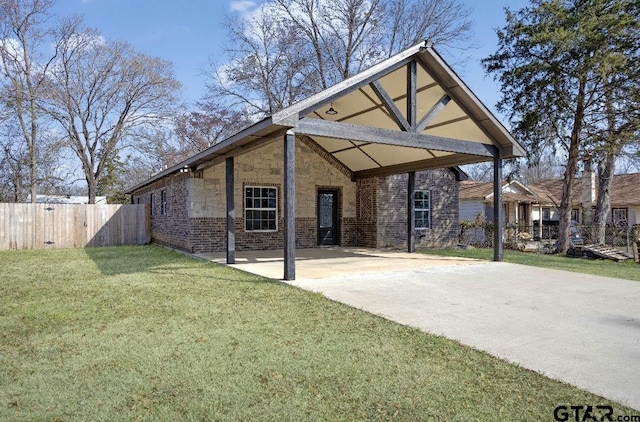 back of property with brick siding, a lawn, fence, a carport, and driveway