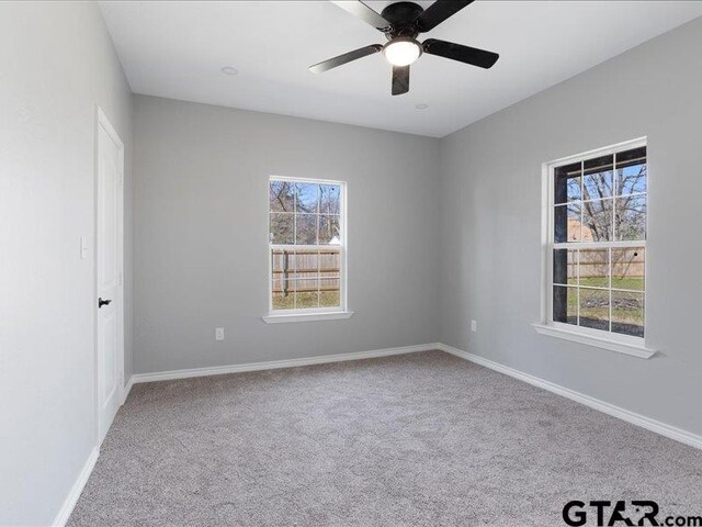 spare room featuring carpet, a healthy amount of sunlight, ceiling fan, and baseboards