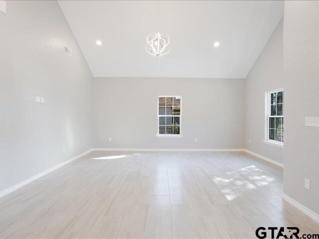 spare room featuring baseboards, high vaulted ceiling, and a notable chandelier