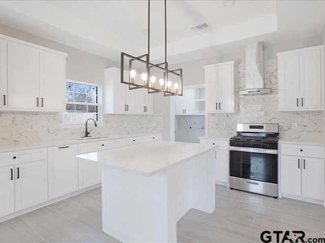 kitchen with stainless steel range with gas cooktop, visible vents, white cabinetry, a sink, and wall chimney exhaust hood