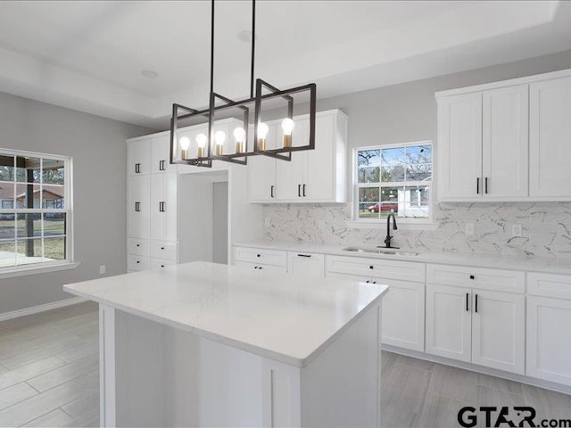 kitchen with tasteful backsplash, a center island, a healthy amount of sunlight, and a sink