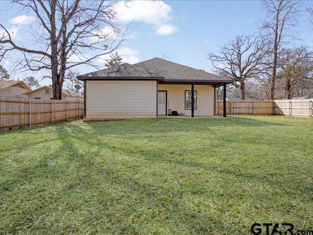 rear view of house featuring a lawn and a fenced backyard