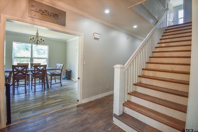 staircase featuring a notable chandelier, wood-type flooring, and ornamental molding