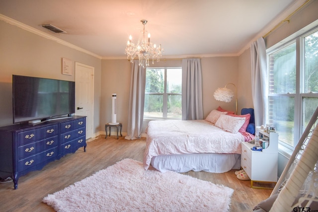 bedroom with crown molding, light hardwood / wood-style floors, and a notable chandelier