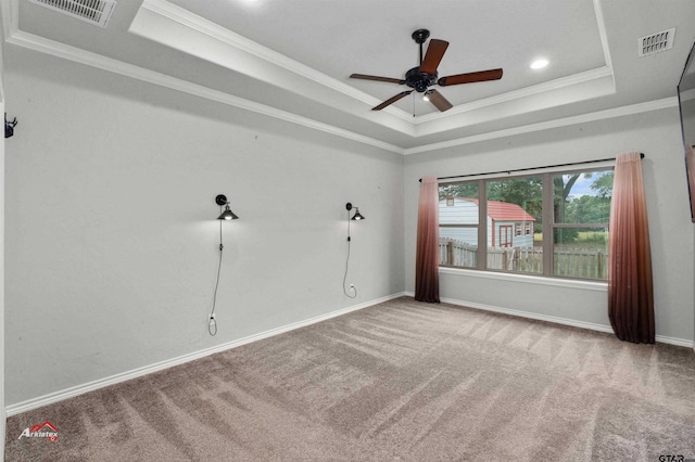 carpeted empty room with ceiling fan, crown molding, and a raised ceiling