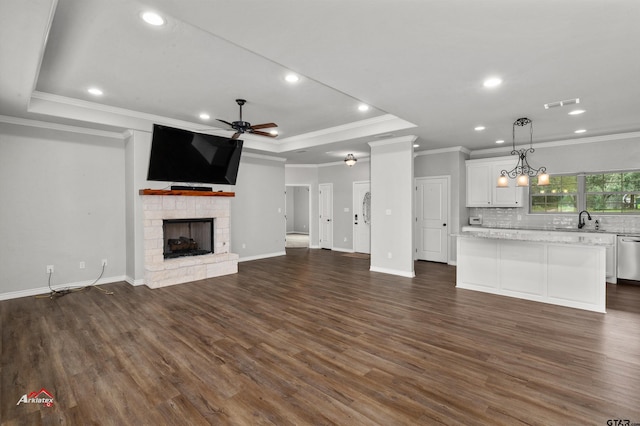 unfurnished living room with a stone fireplace, dark hardwood / wood-style flooring, ornamental molding, and a raised ceiling