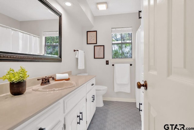 bathroom featuring tile patterned flooring, vanity, toilet, and a healthy amount of sunlight