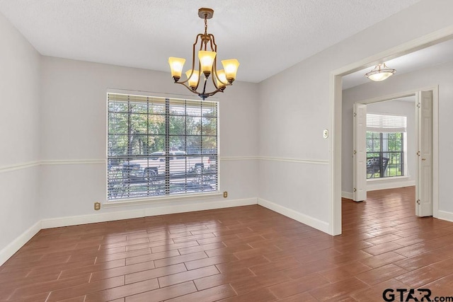 spare room with dark hardwood / wood-style flooring, a chandelier, and a textured ceiling