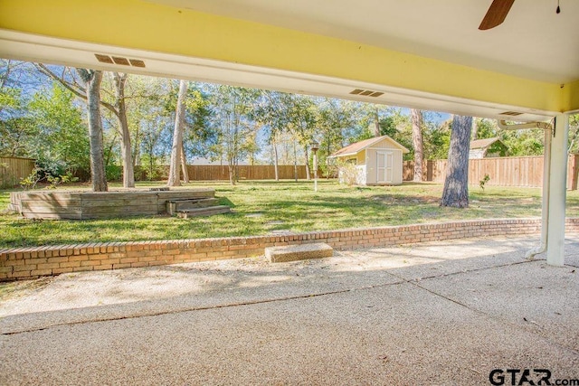 view of yard featuring a patio, ceiling fan, and a storage shed