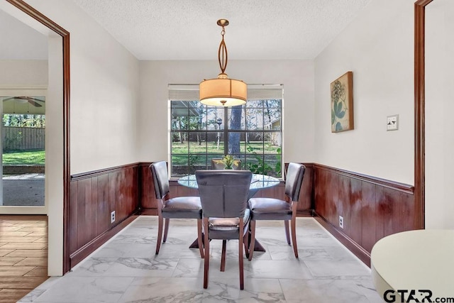 dining area with a textured ceiling and wooden walls