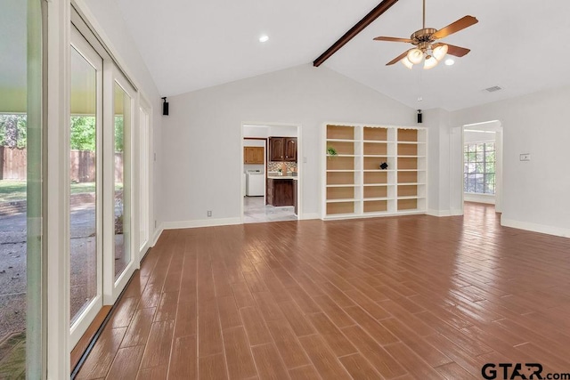 unfurnished living room featuring hardwood / wood-style floors, vaulted ceiling with beams, and a healthy amount of sunlight