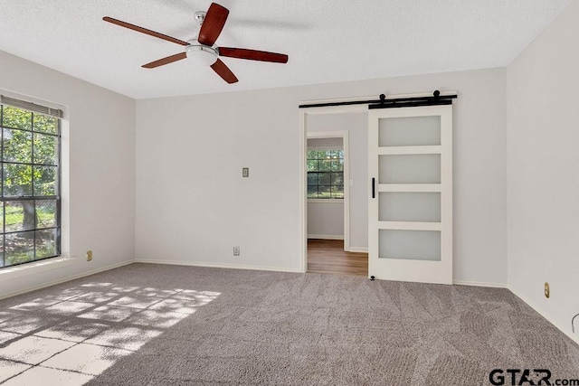 unfurnished room featuring carpet flooring, built in shelves, a textured ceiling, and ceiling fan