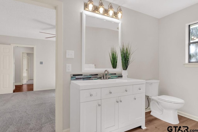 bathroom featuring wood-type flooring, vanity, toilet, and ceiling fan