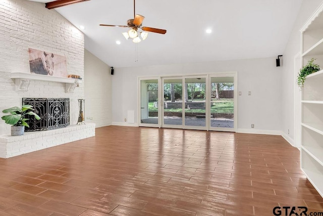 unfurnished living room featuring a brick fireplace, ceiling fan, wood-type flooring, high vaulted ceiling, and beamed ceiling