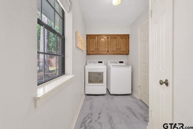 laundry room with washer and clothes dryer, plenty of natural light, cabinets, and a textured ceiling