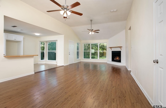 16530 Echo Glen Dr, Tyler, TX 75703 - unfurnished living room featuring wood finished floors, a ceiling fan, a brick fireplace, baseboards, and lofted ceiling