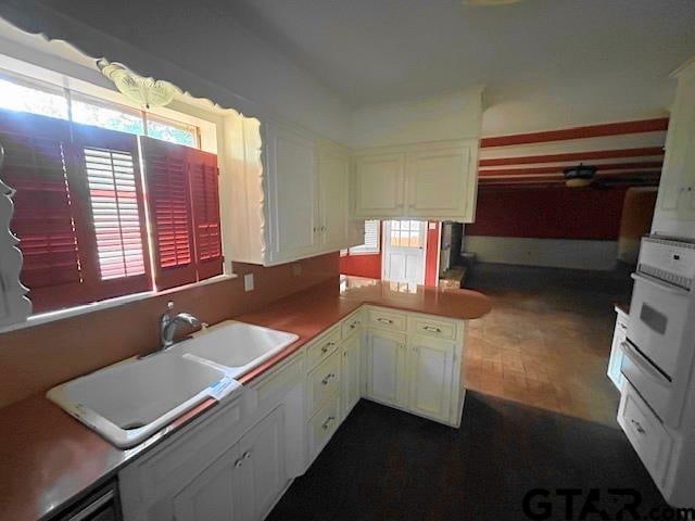 kitchen with oven, white cabinetry, sink, and kitchen peninsula