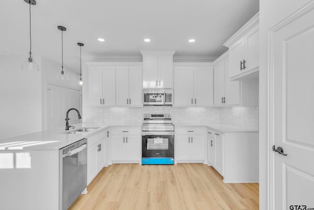 kitchen with backsplash, stainless steel appliances, sink, white cabinets, and hanging light fixtures