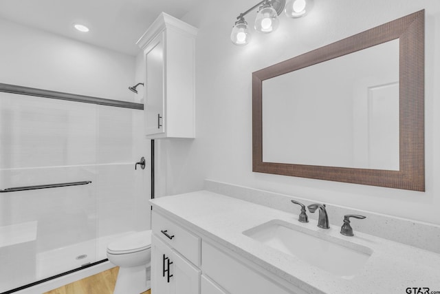 bathroom with hardwood / wood-style flooring, vanity, toilet, and walk in shower