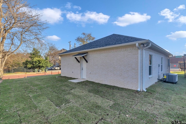 rear view of property featuring a lawn and cooling unit