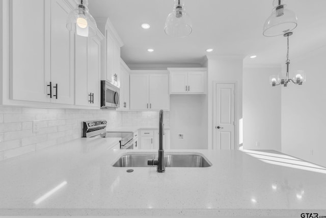 kitchen with sink, decorative light fixtures, decorative backsplash, white cabinets, and appliances with stainless steel finishes