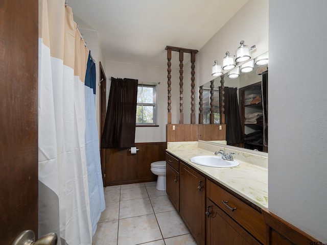 full bathroom with toilet, vanity, wooden walls, wainscoting, and tile patterned flooring