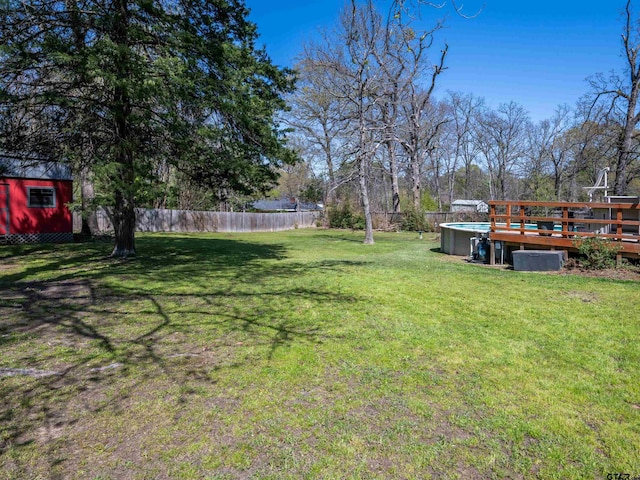 view of yard with fence, a wooden deck, and an outdoor structure