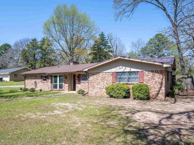 ranch-style home with a chimney, brick siding, metal roof, and a front lawn