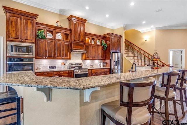 kitchen with crown molding, a kitchen breakfast bar, tasteful backsplash, and appliances with stainless steel finishes