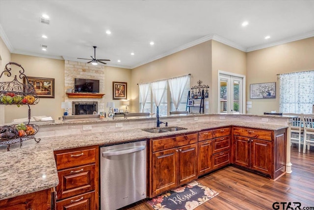 kitchen featuring a sink, stainless steel dishwasher, a fireplace, light stone countertops, and dark wood-style flooring