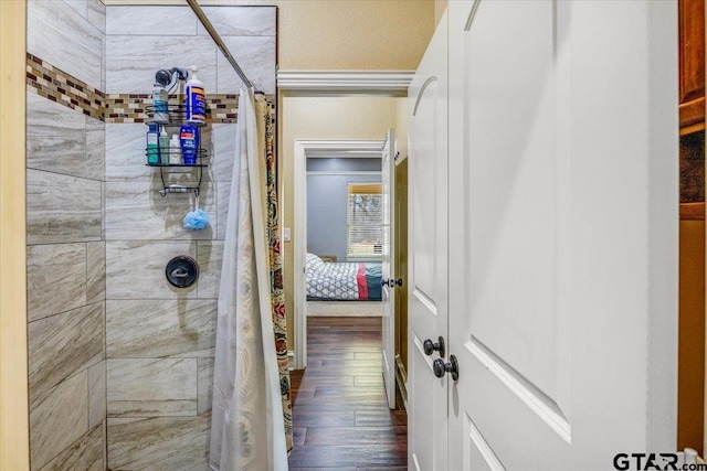 full bath with a tile shower and wood finished floors