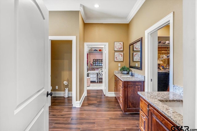 interior space with dark wood finished floors, ornamental molding, baseboards, and a sink