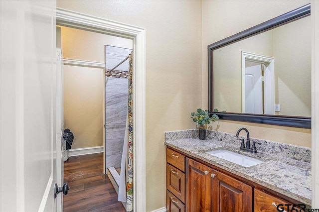 bathroom with baseboards, a shower stall, wood finished floors, and vanity