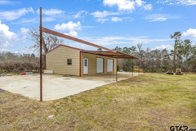 rear view of house featuring a detached garage and a yard