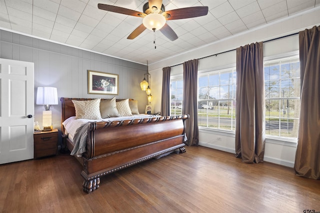 bedroom featuring dark wood finished floors, baseboards, ornamental molding, and a ceiling fan