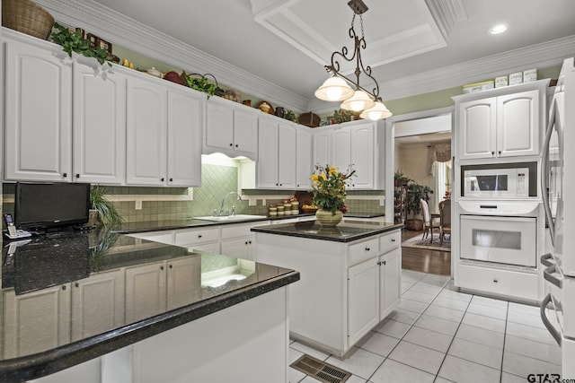 kitchen with sink, white appliances, white cabinetry, and a raised ceiling