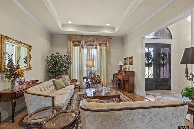 living room with light hardwood / wood-style flooring, a tray ceiling, and ornamental molding