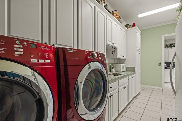 laundry room with crown molding, sink, washing machine and clothes dryer, light tile patterned flooring, and cabinets