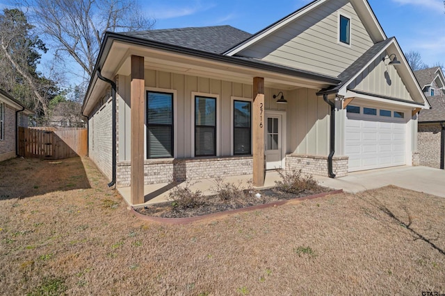 view of front facade with driveway, brick siding, board and batten siding, and fence