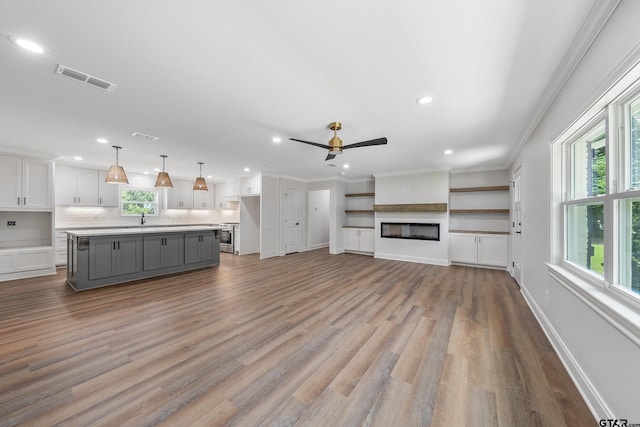2918 Oak Knob Dr, Tyler, TX 75701 - unfurnished living room featuring a sink, recessed lighting, a glass covered fireplace, a ceiling fan, and crown molding
