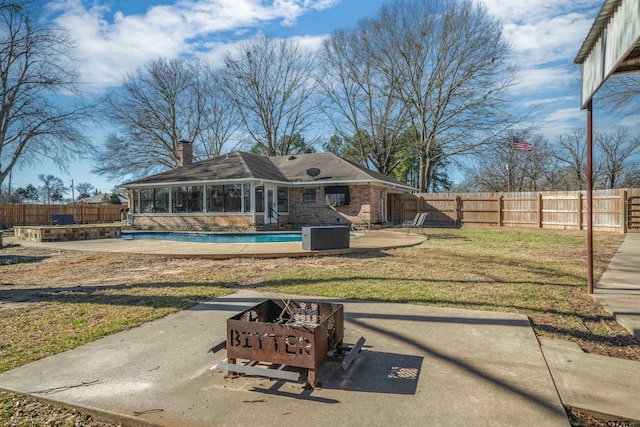 rear view of property with a fenced in pool, an outdoor fire pit, a fenced backyard, and a sunroom