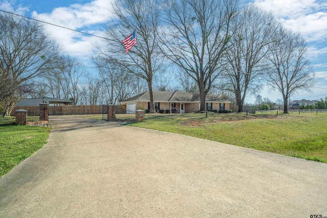 view of front of house featuring a front lawn, driveway, a fenced front yard, an attached garage, and brick siding