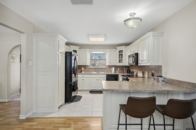 1039 Fm 2909, Canton, TX 75103 - kitchen with black appliances, a peninsula, a breakfast bar area, backsplash, and a sink
