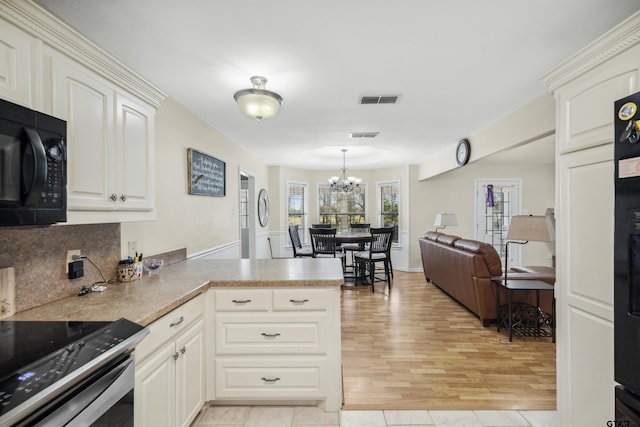 1039 Fm 2909, Canton, TX 75103 - kitchen featuring black microwave, a chandelier, a peninsula, stainless steel electric stove, and decorative backsplash